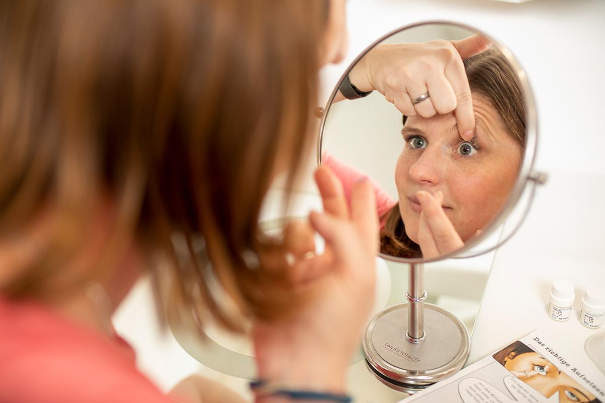 Eine Kundin setzt sich kontaktlinsen ein